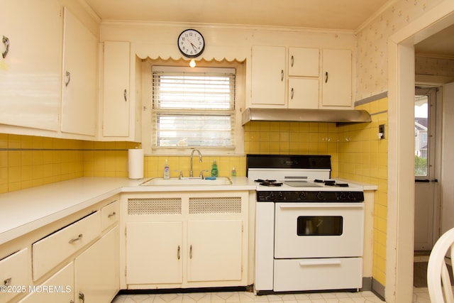 kitchen with a sink, light countertops, white range with electric cooktop, and under cabinet range hood