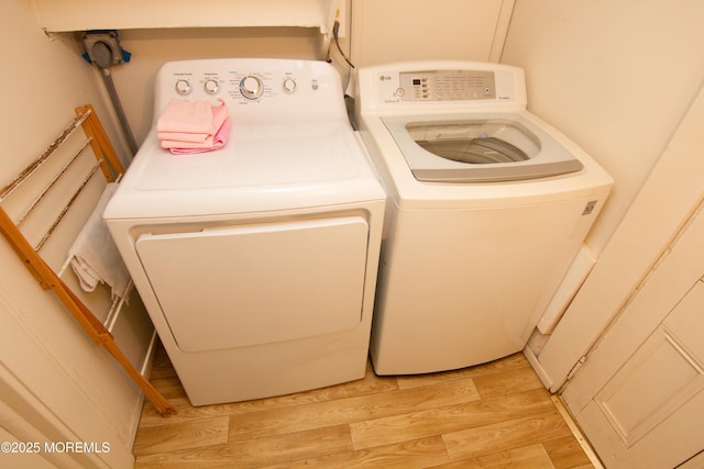 clothes washing area with washing machine and clothes dryer, laundry area, and light wood-type flooring