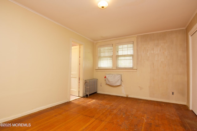 unfurnished room with wood-type flooring, baseboards, crown molding, and radiator heating unit