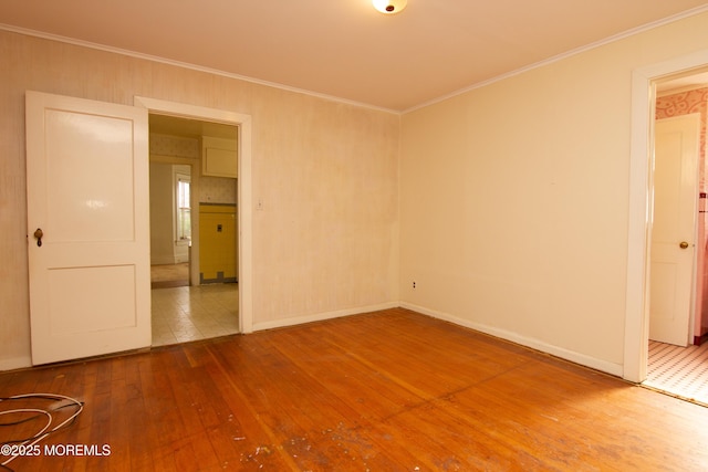 unfurnished room with wood-type flooring, crown molding, and baseboards