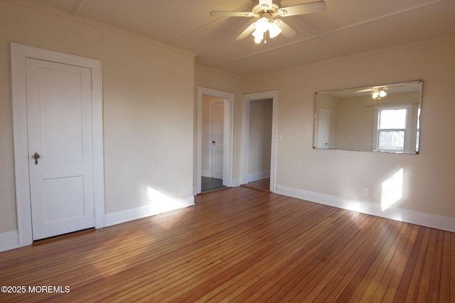 empty room with a ceiling fan, baseboards, ornamental molding, and light wood-style flooring
