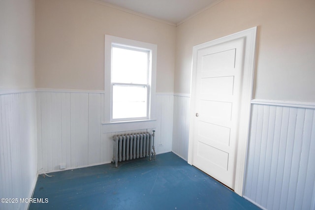unfurnished room featuring ornamental molding, radiator, and wainscoting