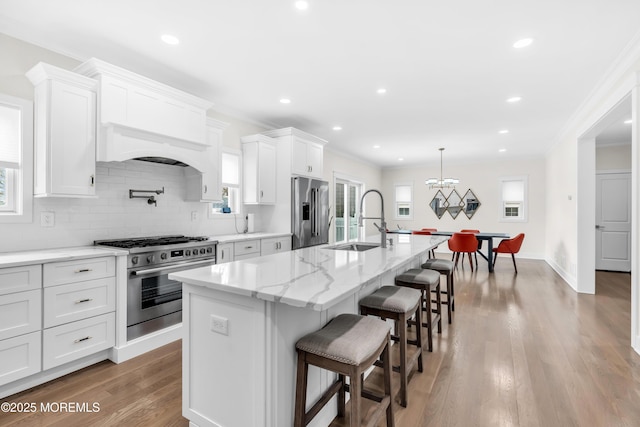 kitchen featuring white cabinetry, a center island with sink, stainless steel appliances, and a sink