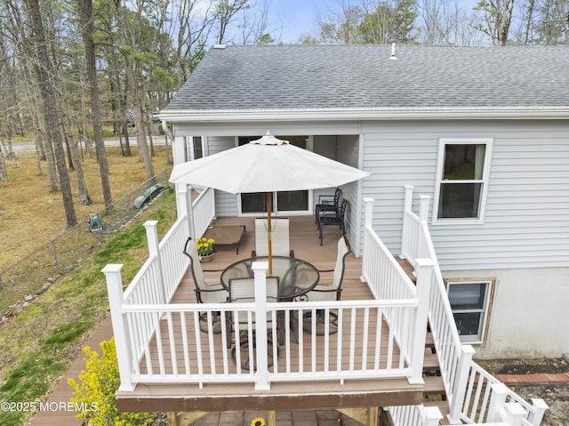 back of property with a wooden deck, outdoor dining space, a shingled roof, and stairs