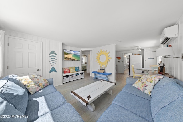 living room featuring an AC wall unit, ceiling fan, and light wood-style floors