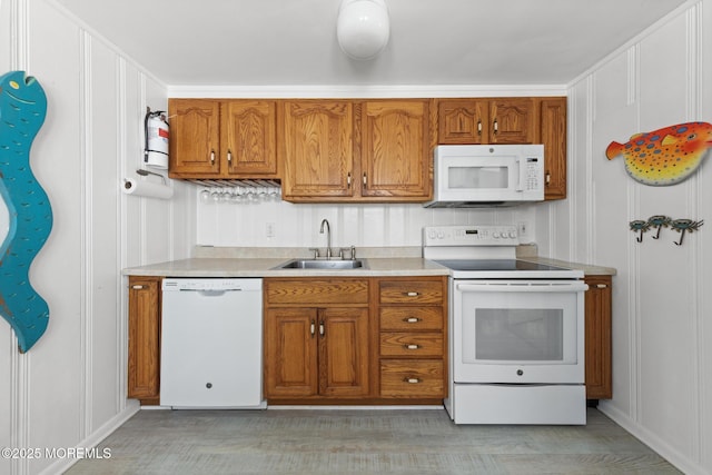 kitchen featuring light countertops, brown cabinets, a sink, and white appliances