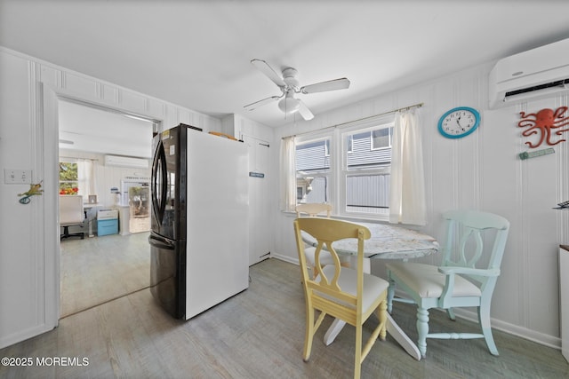 dining area featuring an AC wall unit, ceiling fan, and light wood finished floors