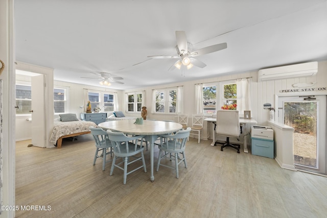 dining area featuring light wood-style flooring, a wall mounted air conditioner, and ceiling fan