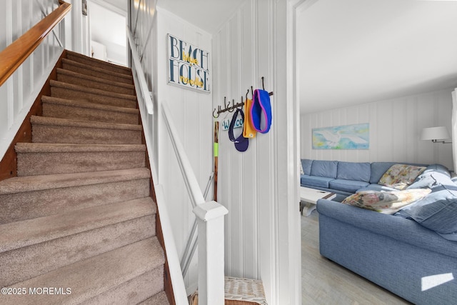 staircase featuring a decorative wall and wood finished floors