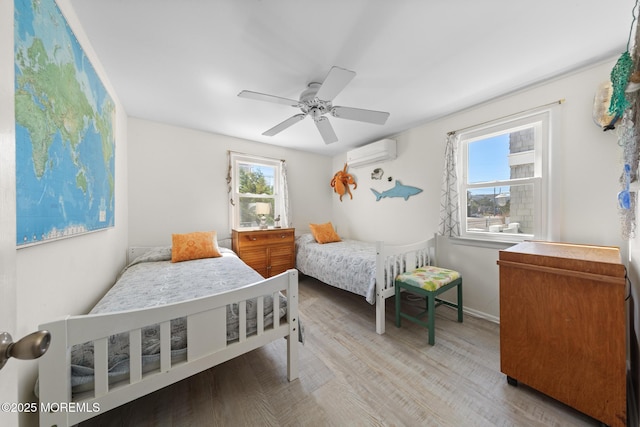 bedroom with multiple windows, a wall mounted AC, wood finished floors, and a ceiling fan