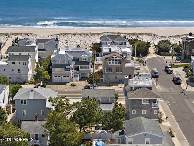 drone / aerial view featuring a water view, a beach view, and a residential view