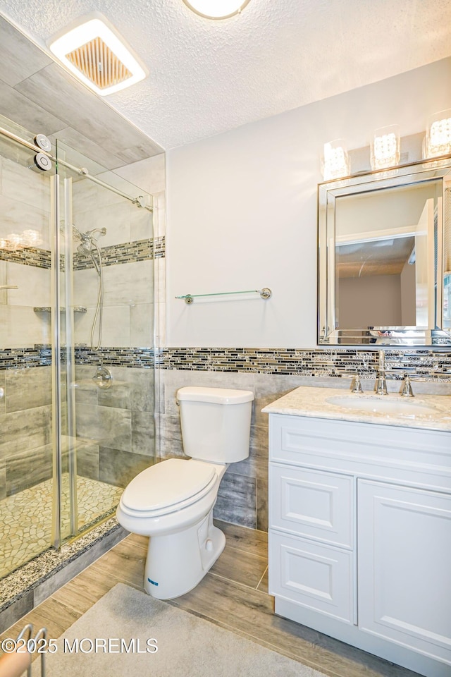 13 Gatley Close Unit 1000, Freehold, NJ 07728 - full bathroom featuring vanity, toilet, a shower stall, tile walls, and wood finished floors