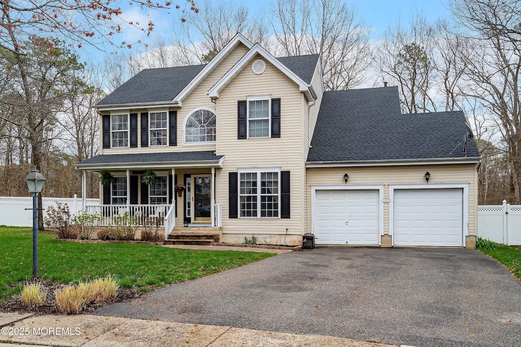 view of front of home featuring a front yard, a porch, a garage, fence, and driveway