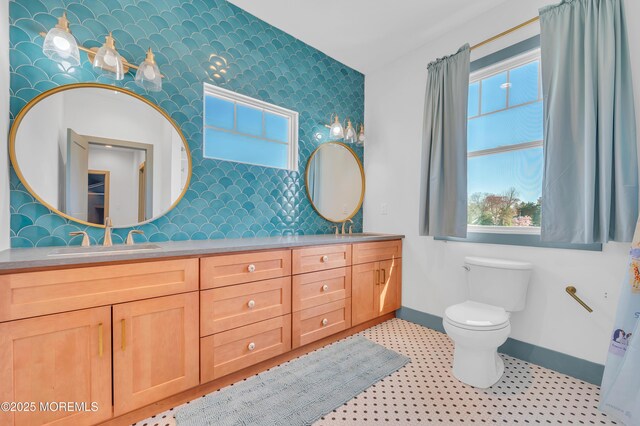 1417 Holmes Ave, Toms River, NJ 08753 - bathroom featuring baseboards, an accent wall, wallpapered walls, toilet, and double vanity