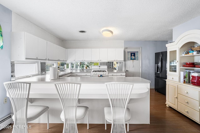 kitchen with light countertops, a peninsula, white range with gas cooktop, black refrigerator with ice dispenser, and a breakfast bar