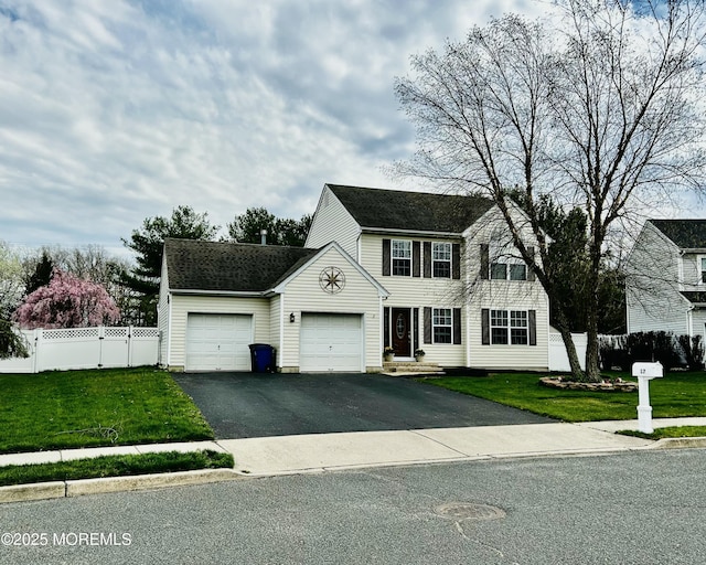 colonial home with fence, driveway, a front yard, and a garage