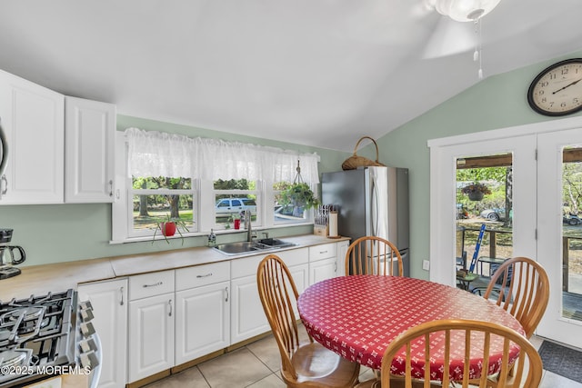 kitchen with vaulted ceiling, a sink, light countertops, stainless steel appliances, and white cabinetry