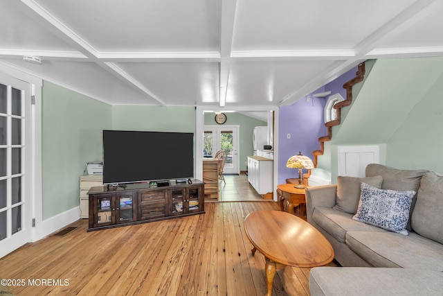 living area featuring visible vents, light wood-style flooring, stairs, and beam ceiling