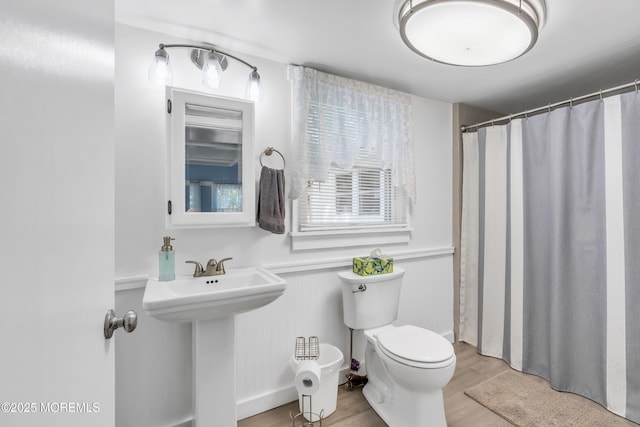 full bathroom featuring a sink, toilet, a wainscoted wall, wood finished floors, and a shower with curtain