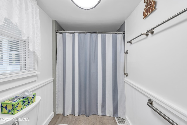 bathroom featuring visible vents, a wainscoted wall, toilet, a decorative wall, and a shower with shower curtain