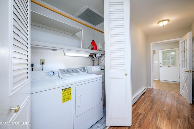 clothes washing area with baseboard heating, water heater, light wood-style flooring, washing machine and dryer, and laundry area