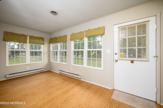 unfurnished sunroom featuring a baseboard heating unit and visible vents