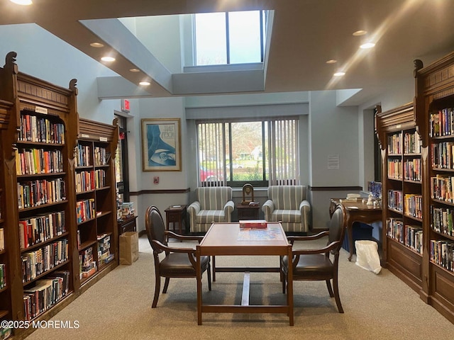 living area with wall of books, carpet flooring, and recessed lighting