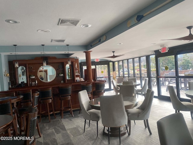 dining space with a community bar, visible vents, ornate columns, and ceiling fan