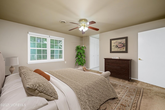 bedroom featuring light colored carpet, a ceiling fan, visible vents, and a closet