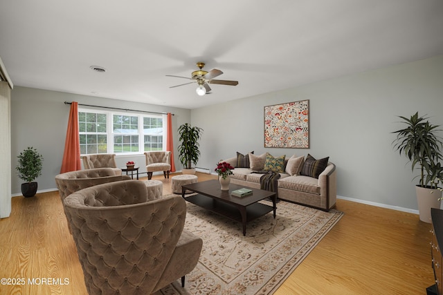 living area featuring light wood finished floors, visible vents, a baseboard heating unit, baseboards, and ceiling fan