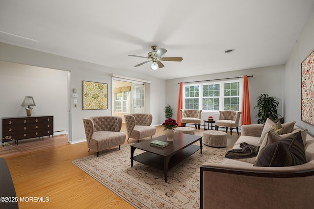 living area featuring visible vents, a ceiling fan, light wood-type flooring, baseboards, and a baseboard radiator