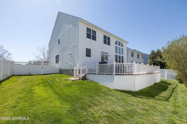 rear view of house featuring a lawn, a fenced backyard, a wooden deck, and a gate