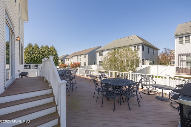 wooden deck with a residential view, fence, and outdoor dining space