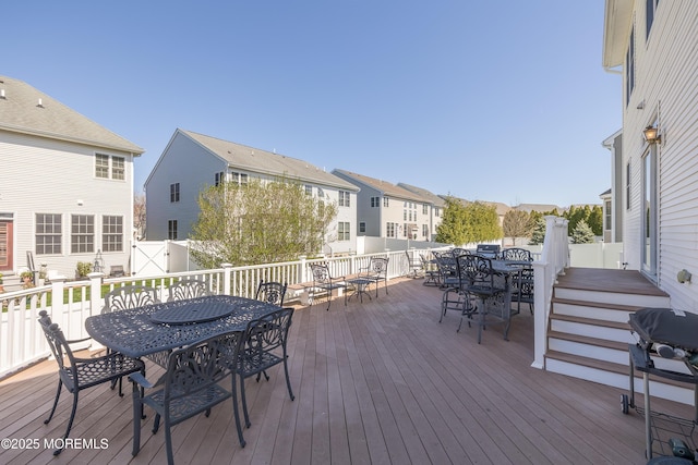 wooden terrace with outdoor dining area, a residential view, and a grill