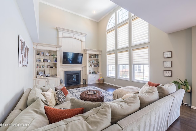 living area with crown molding, baseboards, dark wood finished floors, and a towering ceiling