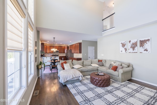 living area featuring a towering ceiling, visible vents, baseboards, recessed lighting, and dark wood-type flooring