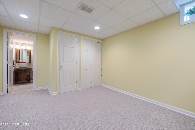 unfurnished bedroom featuring carpet floors, a paneled ceiling, and visible vents
