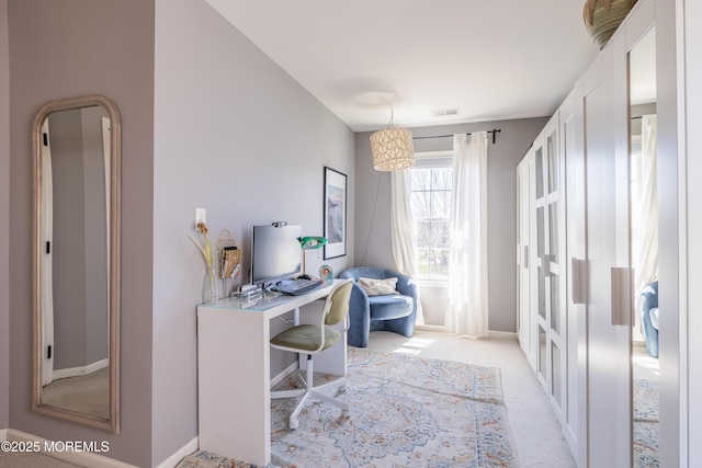 office area with baseboards, visible vents, and light carpet