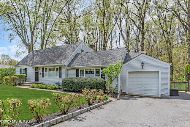 ranch-style home with a shingled roof, driveway, a chimney, and a front lawn