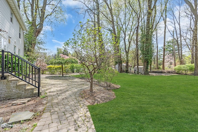 view of green lawn with a patio and stairway