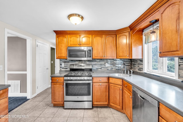 kitchen featuring stainless steel appliances, a sink, decorative backsplash, and brown cabinetry