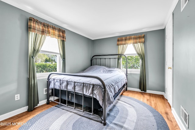 bedroom featuring crown molding, multiple windows, wood finished floors, and baseboards