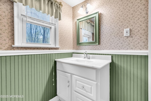 bathroom featuring wainscoting, wallpapered walls, and vanity