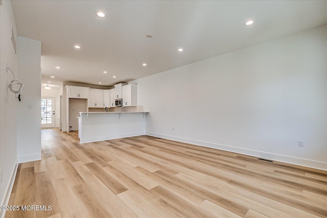unfurnished living room with light wood-style floors, recessed lighting, and visible vents