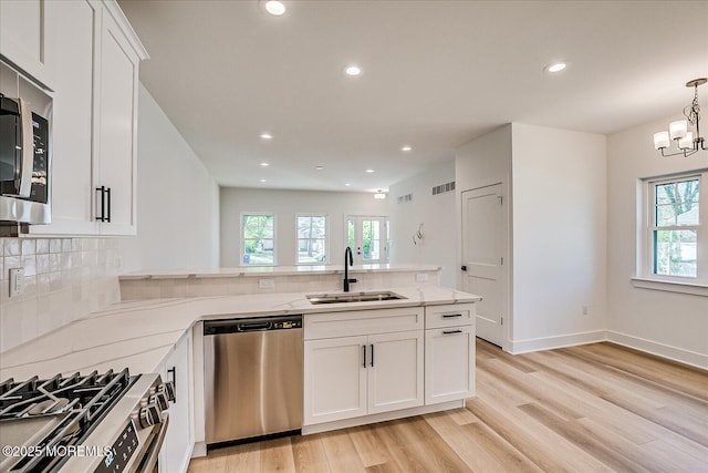 kitchen with light wood-type flooring, a sink, appliances with stainless steel finishes, and a wealth of natural light