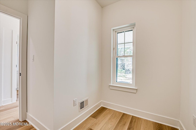 spare room with baseboards, light wood finished floors, and visible vents