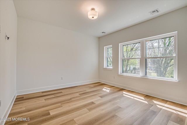 empty room featuring baseboards, visible vents, and light wood-style floors
