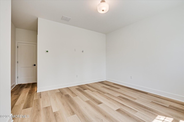 empty room featuring light wood-type flooring, baseboards, and visible vents