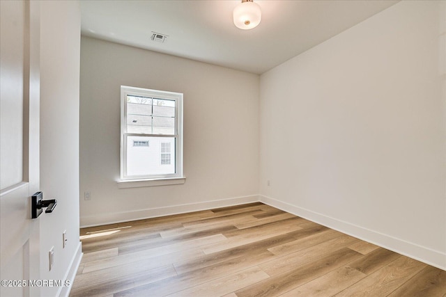 spare room featuring visible vents, light wood-style floors, and baseboards