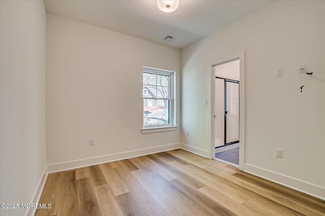 unfurnished room featuring baseboards, visible vents, and wood finished floors